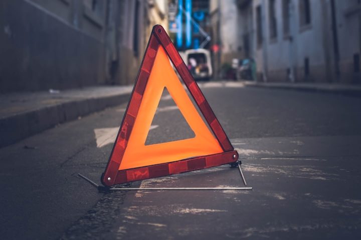 Warnschild in Form eines Dreiecks auf einer Straße, um auf eine Gefahrenstelle hinzuweisen.
