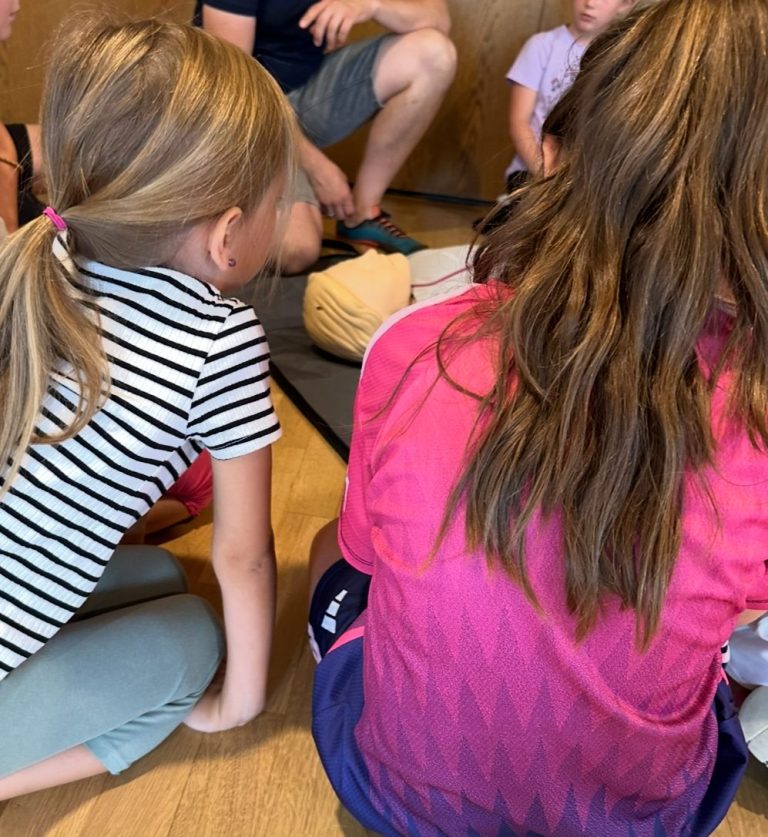 Kinder sitzen im Kreis und beobachten aufmerksam eine Aktivität.