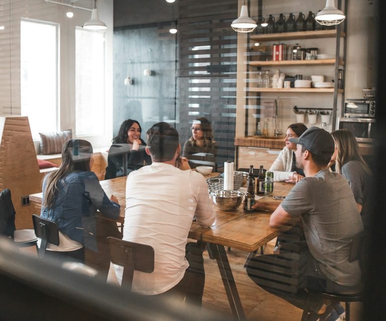 Besprechung in einem modernen Raum mit mehreren Personen um einen Tisch.