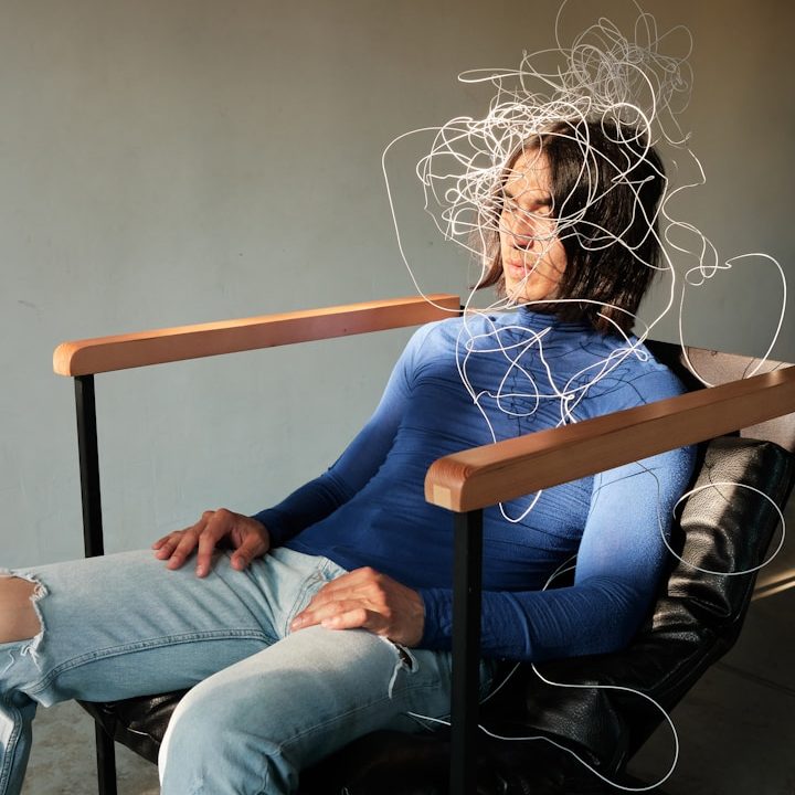 Weniger Stress und Burnout durch BGM Eine Person sitzt entspannt in einem Stuhl mit zerzaustem Haar und einem blauen Pullover.