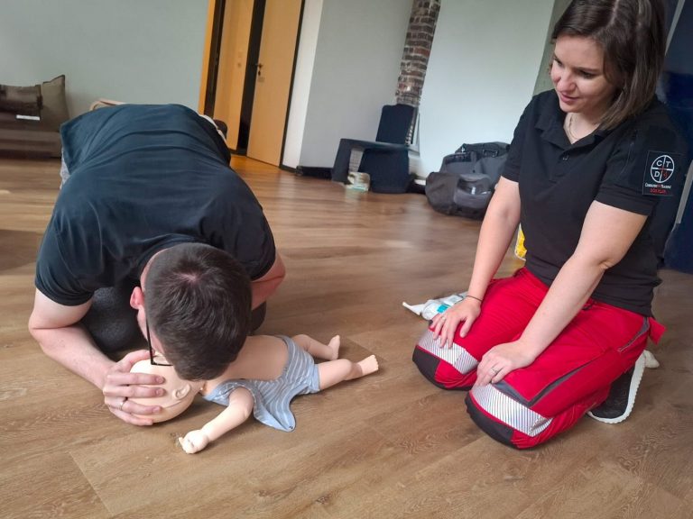 Mann führt CPR an einer Puppe durch, während eine Frau daneben beobachtet.