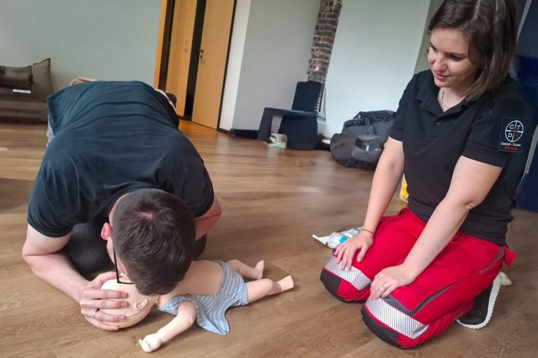 Eine Person führt eine Herz-Lungen-Wiederbelebung an einer Puppe durch, während eine andere zuschaut.