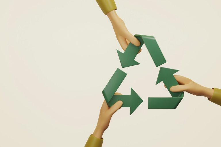 Drei Hände halten ein grünes Recycling-Symbol vor neutralem Hintergrund.