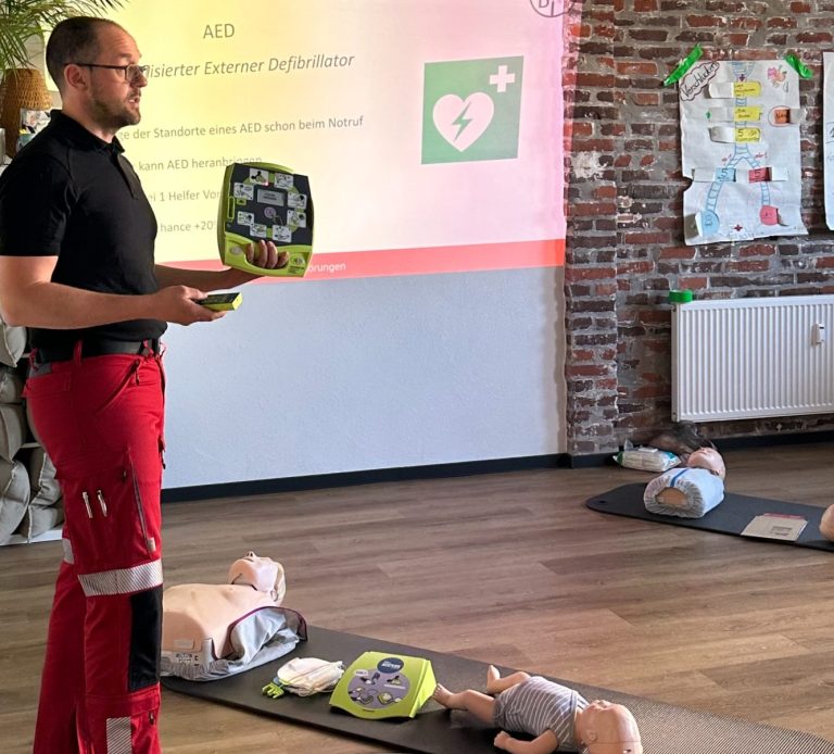 Mann in Uniform hält Defibrillator vor Präsentation über Erste Hilfe.