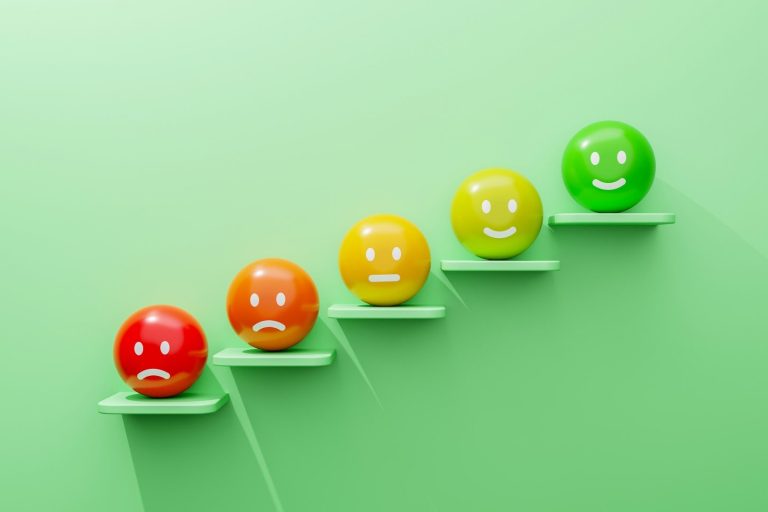 Fünf bunte Smileys auf Stufen; von traurig bis glücklich.